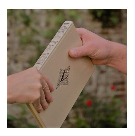 Fotografía de una mano sujetando un libro y otra mano recibiendo ese libro, o sea que alguien le da un libro a otra persona